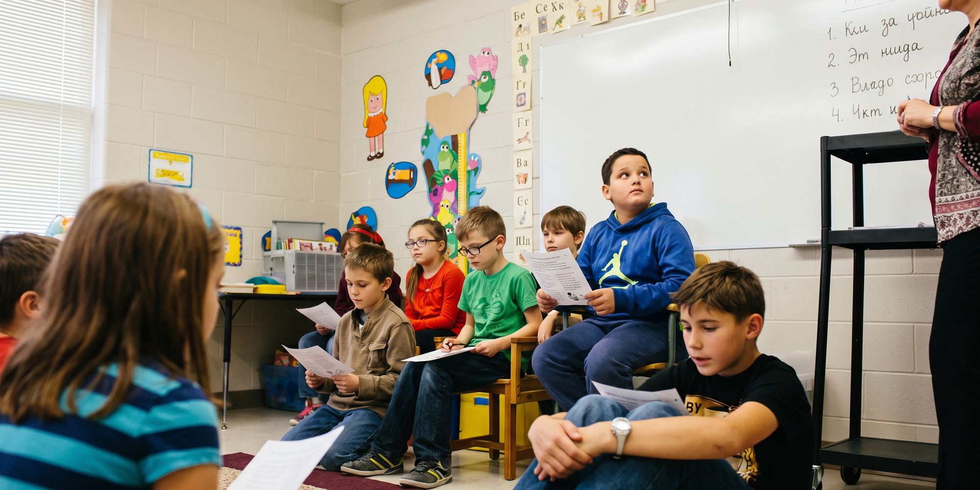 Children seated together in a community school classroom, following a lesson.