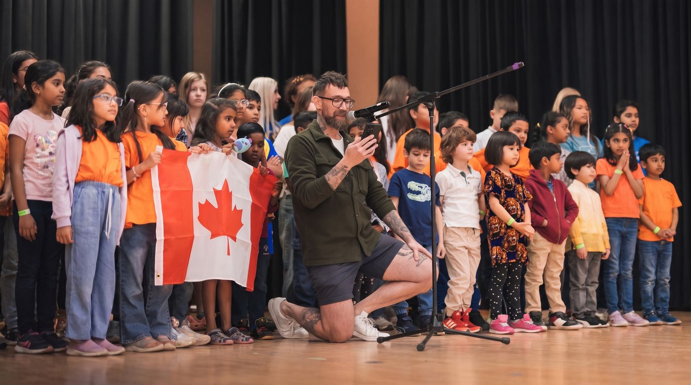 Children on stage holding a Canadian flag during a community showcase.